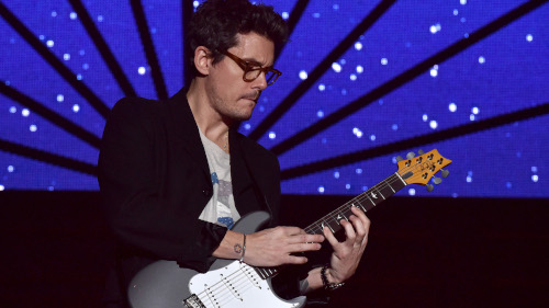 John Mayer playing an electric guitar.