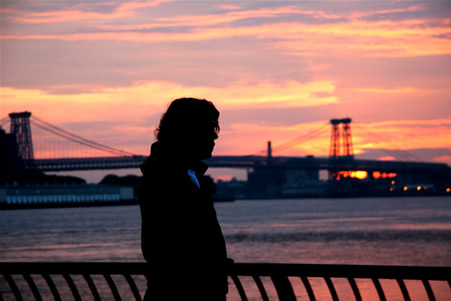 John Mayer in front of NYC skyline with sunset.