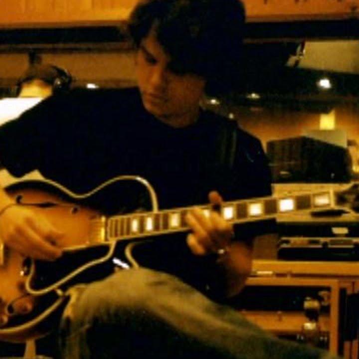 john mayer playing guitar in a studio.
